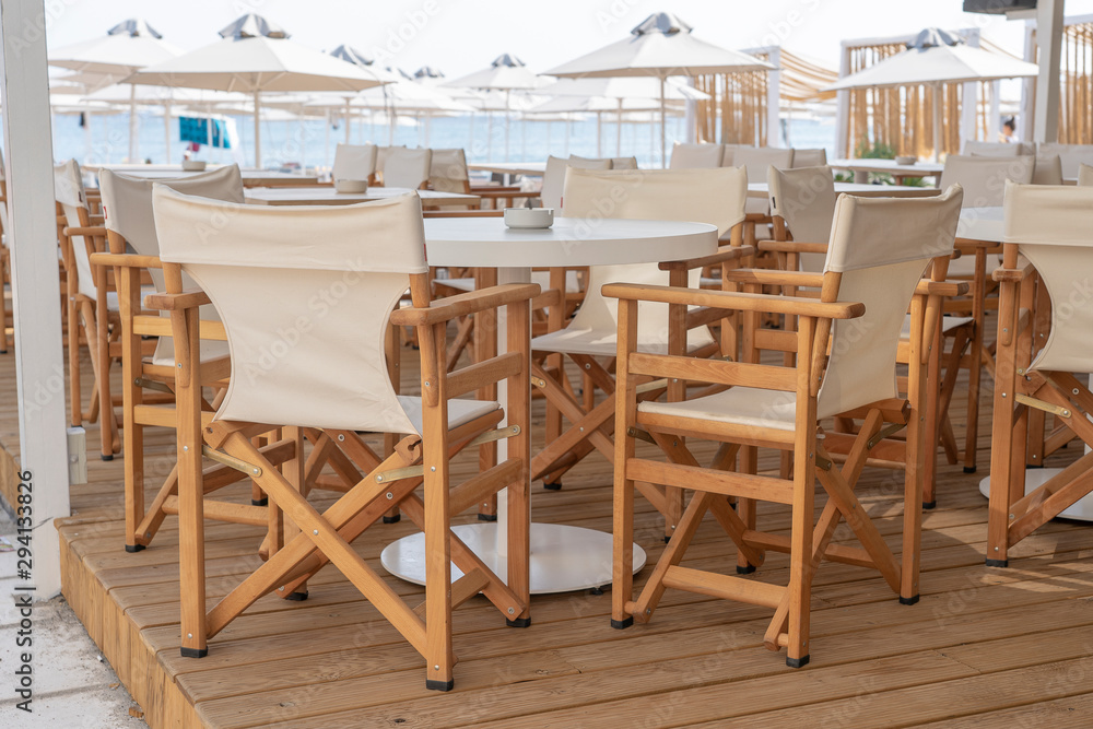 Empty table and chairs in restaurant, Greece. Beach cafe near sea, outdoors. Travel and vacation concept