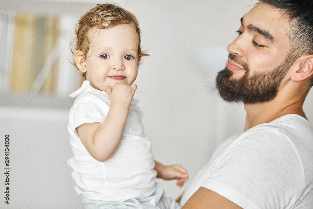 young positive bearded man holding baby in his hands, looking at her with tender expression. close up photo. happy parenthood. close up portrait young positive bearded man holding baby in his hands, looking at her with tender expression. close up photo. happy parenthood. close up portrait