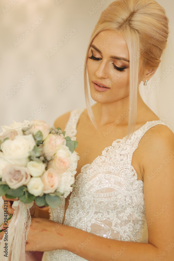 Naklejka premium Portrait of gorgeous bride at home. Charming woman with bouquet. Morning of beautiful bride. Wedding day