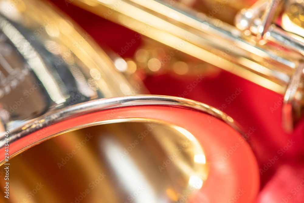 Beautiful macro photo of the details of a wind instrument of a golden alto saxophone on a red background