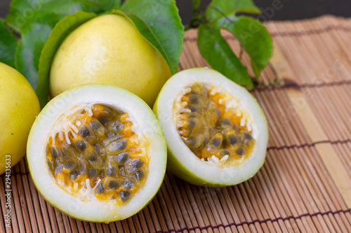 There are yellow Passion fruits with green leaves on wooden table background.