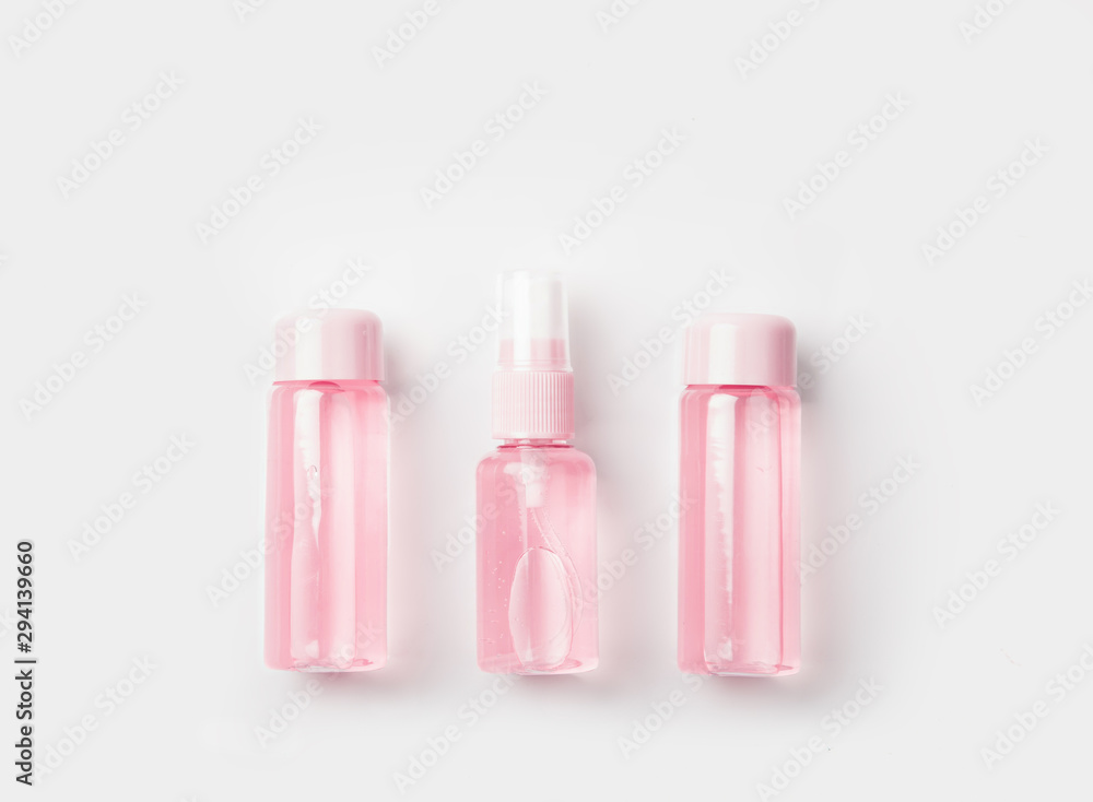 Three bottles of tonic or lotion sprinkled with water on pink or powder background. Freshness and body care. Female cosmetics. Micellar water. Travel set of face care cosmetic Three bottles of tonic or lotion sprinkled with water on pink or powder background. Freshness and body care. Female cosmetics. Micellar water. Travel set of face care cosmetic
