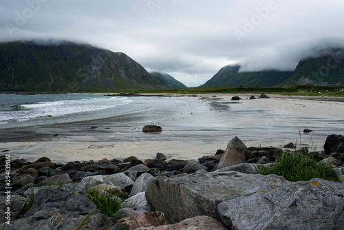 Beautiful nature landscape in North. Scenic outdoors view. Ocean with waves and mountains. Big dark stones. Dramatic storm clouds. Extreme weather, rain and wind. Explore Norway, summer adventure