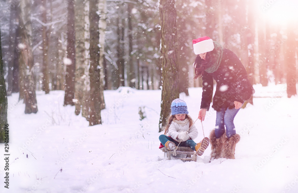 A winter fairy tale,in the forest. A girl on a sled with gifts on the eve of the new year in the park. Two sisters walk in a New Year's park and ride a sled with gifts.