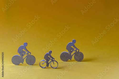 Figurines de cyclistes en métal sur fond jaune