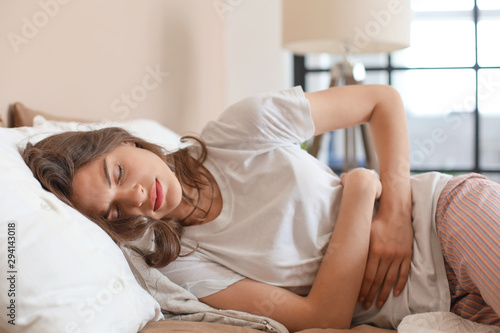 Sick woman on bed concept of stomachache. photo
