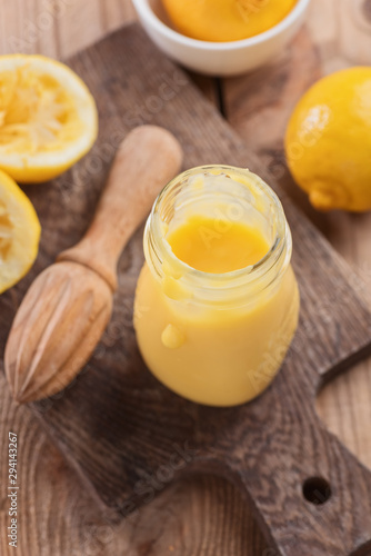 Lemon curd in a glass jar on a wooden background, ingredients for cooking, lemon kyrd recipe