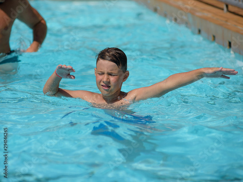 Cute European boy dancing aqua Zumba in hotel’s pool during his summer vacations. Healthy active childhood concept. © Artem