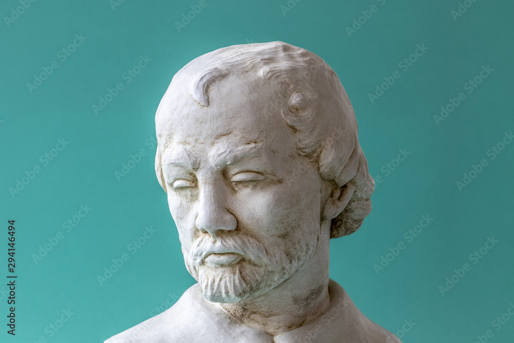Sculpture d'un visage d'homme sur fond bleu turquoise