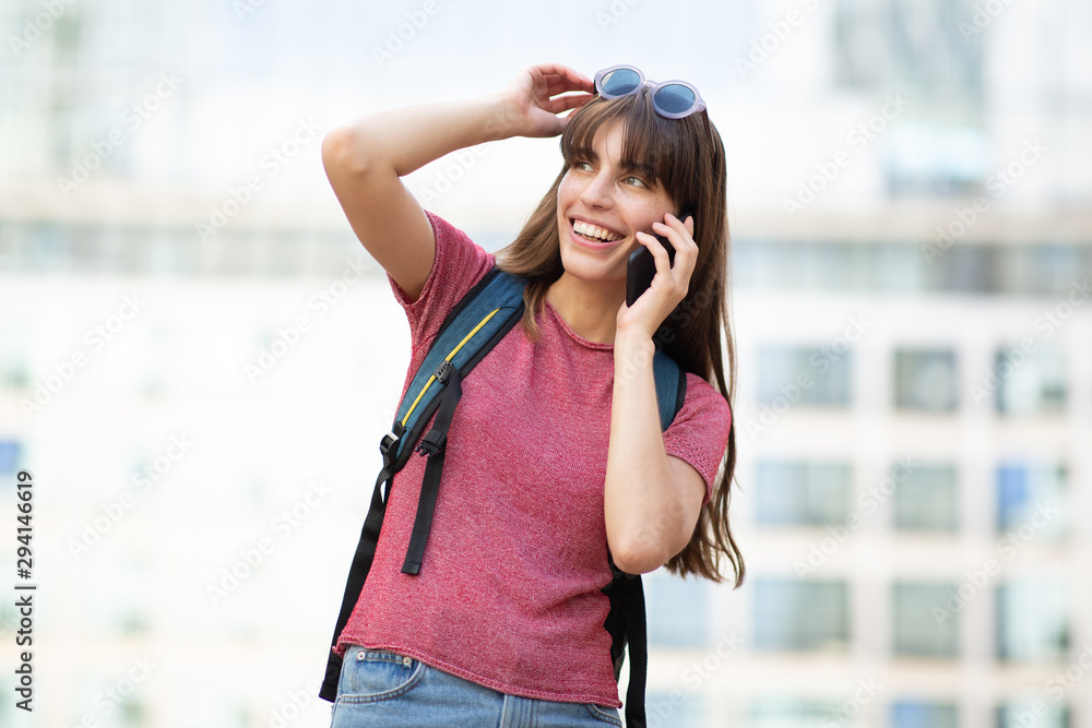 young laughing woman walking and talking with phone and bag in city