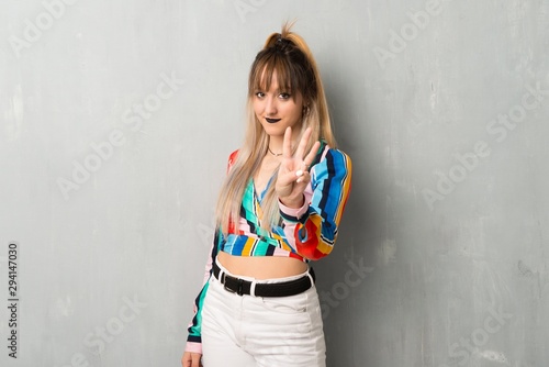 Young girl with colorful clothes happy and counting three with fingers