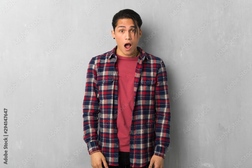 Man over grunge wall with surprise and shocked facial expression Man over grunge wall with surprise and shocked facial expression