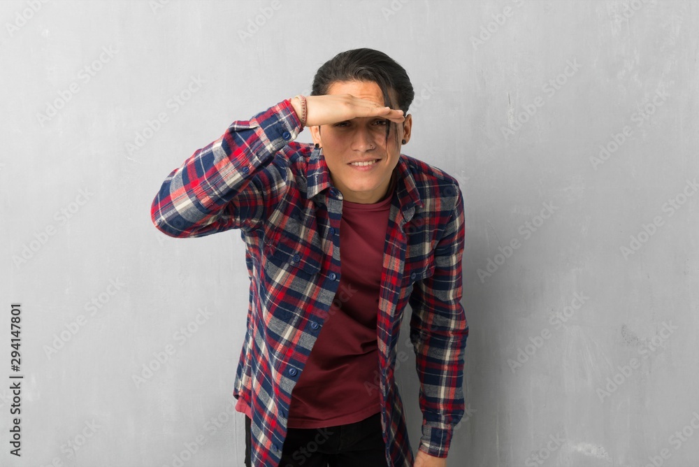 Man over grunge wall looking far away with hand to look something Man over grunge wall looking far away with hand to look something