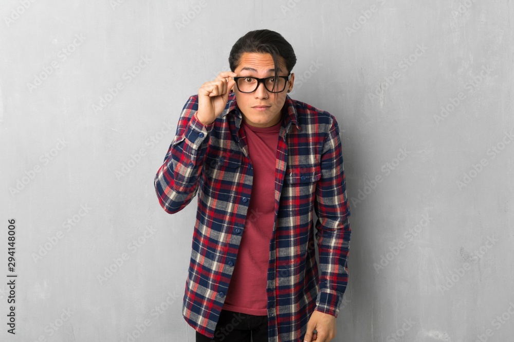 Man over grunge wall with glasses and surprised