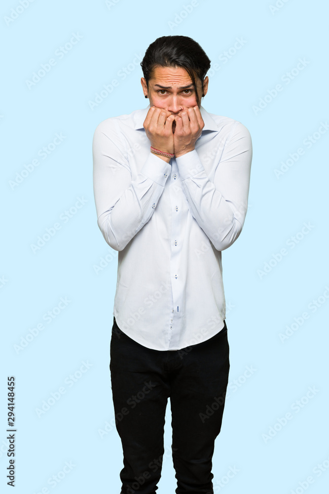 Handsome man is a little bit nervous and scared putting hands to mouth over isolated blue background Handsome man is a little bit nervous and scared putting hands to mouth over isolated blue background