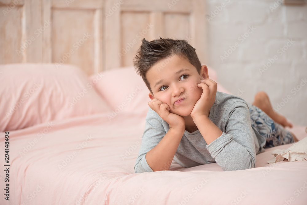 Portrait of a funny brunette boy with a displeased face in the bedroom Portrait of a funny brunette boy with a displeased face in the bedroom