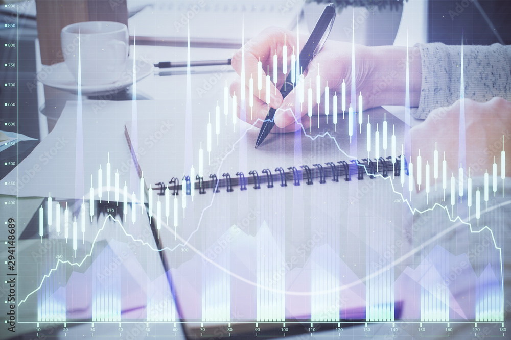 Hand taking notes in notepad. Forex chart holograms in front. Concept of research. Double exposure Hand taking notes in notepad. Forex chart holograms in front. Concept of research. Double exposure