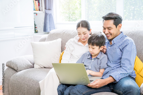 Parent and child playing internet computer laptop together in the living room