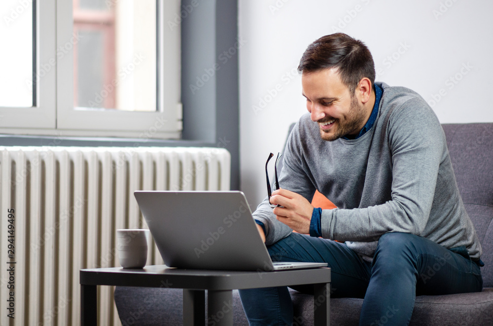 Fototapeta premium Happy freelancer working from home, sitting on a sofa
