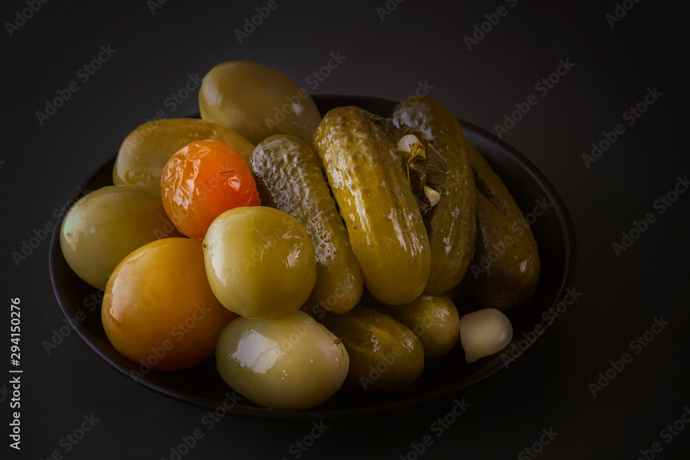 Pickles and tomatoes on a dark background. Low key. Copy space Pickles and tomatoes on a dark background. Low key. Copy space