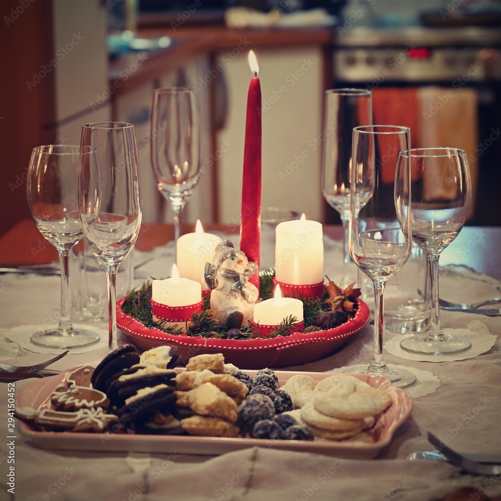 Beautifully set table for Christmas holidays. Candies, candles and Christmas decorations - decorated home on Christmas Eve.