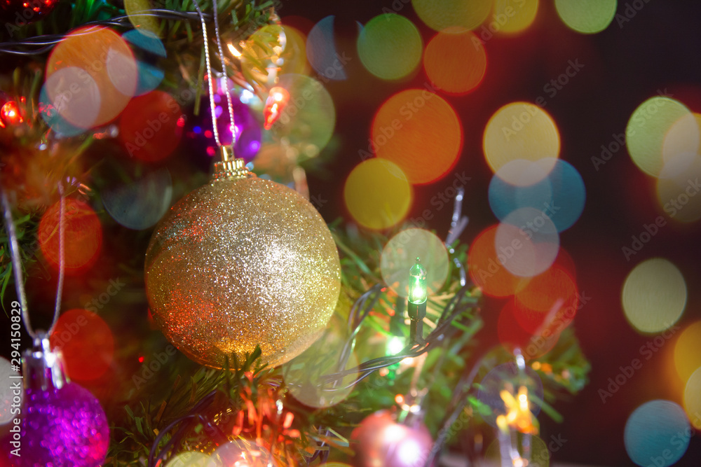 Christmas decoration. Hanging gold balls on pine branches christmas tree garland and ornaments over abstract bokeh background with copy space.