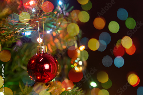 Christmas decoration. Hanging red balls on pine branches christmas tree garland and ornaments over abstract bokeh background with copy space.