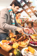 Thanksgiving Celebration Tradition Family Dinner Concept.family having holiday dinner and cutting turkey.Young black adult woman and her daughter happy..