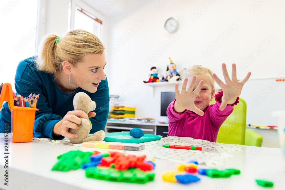 Fototapeta premium Toddler girl in child occupational therapy session doing sensory playful exercises with her therapist.