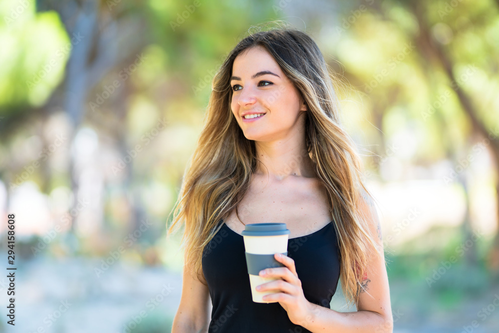 Young girl at outdoors in a park holding coffee to take away Young girl at outdoors in a park holding coffee to take away