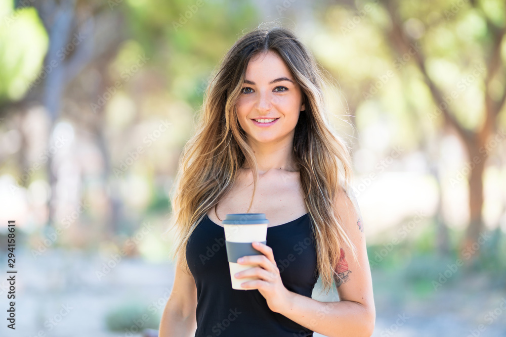 Young girl at outdoors in a park holding coffee to take away Young girl at outdoors in a park holding coffee to take away