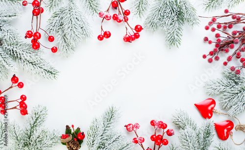 Christmas border. Xmas background composition with green fir branch, red holly berries and snow. Xmas flat lay top view with copy space for text
