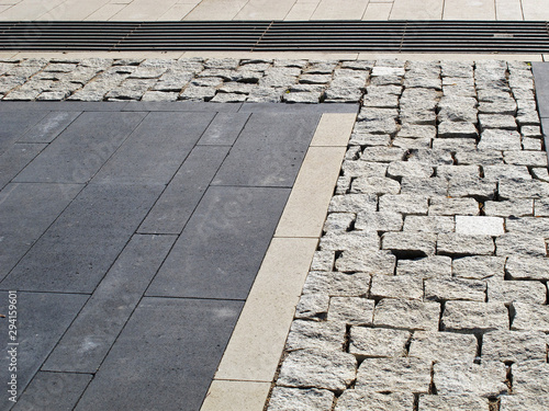 Sidewalk tiles of different shapes in shades of gray