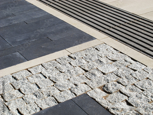 Sidewalk tiles of different shapes in shades of gray