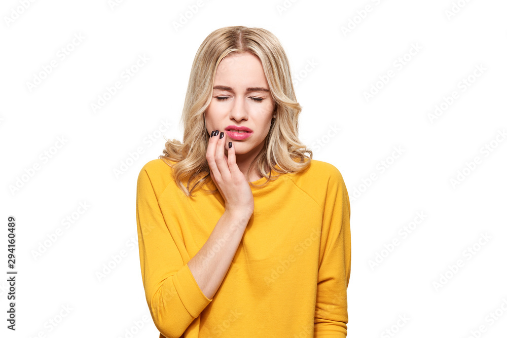 Young Woman Suffering From Toothache. Tooth Pain And Dentistry background. Beautiful Young Woman Suffering From Terrible Teeth Pain, Touching Cheek With Hand. Young Woman Suffering From Toothache. Tooth Pain And Dentistry background. Beautiful Young Woman Suffering From Terrible Teeth Pain, Touching Cheek With Hand.