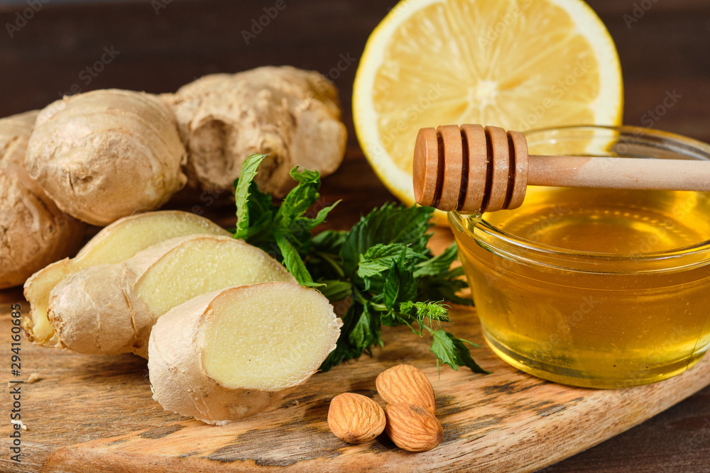 honey with ginger, lemon and mint and nuts on wooden Board and grey background. Close up honey with ginger, lemon and mint and nuts on wooden Board and grey background. Close up