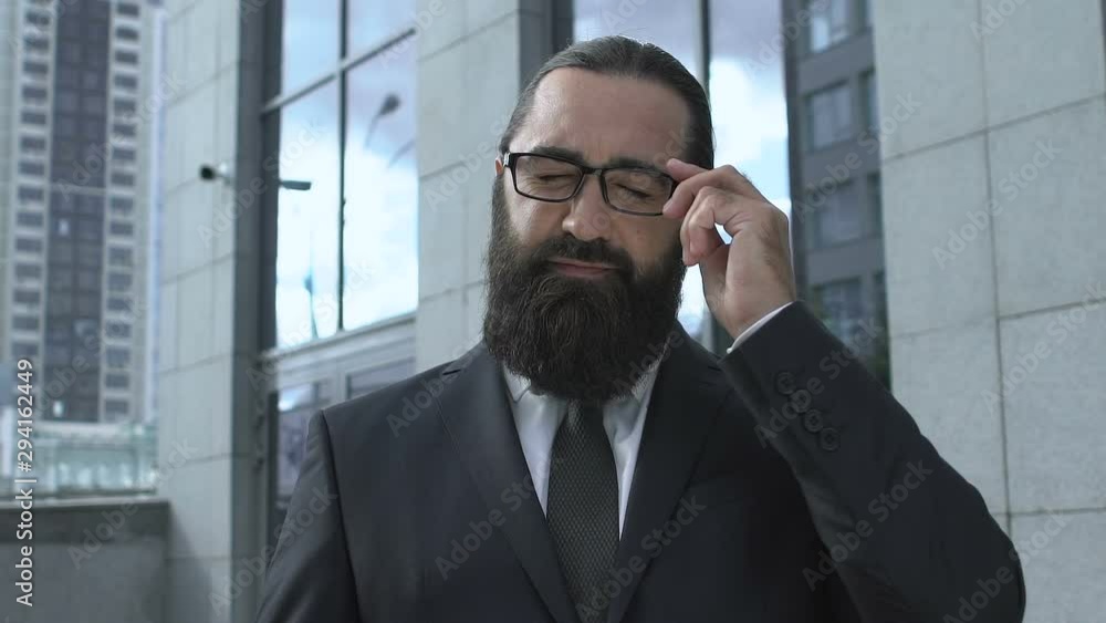 Sick businessman taking off glasses rubbing temples high blood pressure headache Sick businessman taking off glasses rubbing temples high blood pressure headache