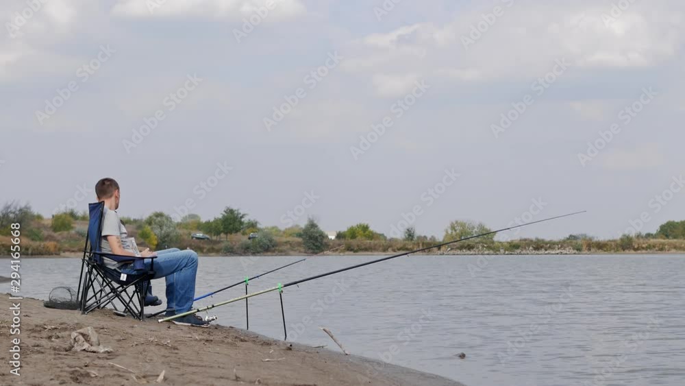 Father and son are fishing while sitting on chairs by the lake. Real time 4k footage Father and son are fishing while sitting on chairs by the lake. Real time 4k footage
