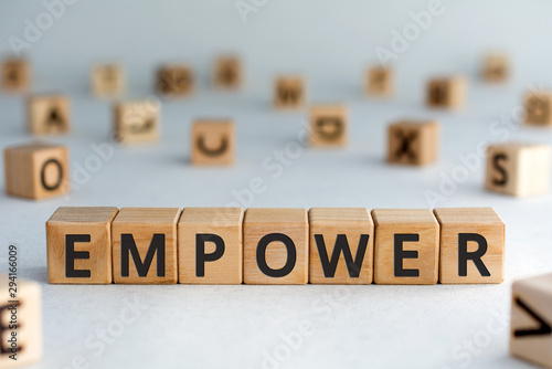 empower - word from wooden blocks with letters, empower concept, random letters around, white  background photo