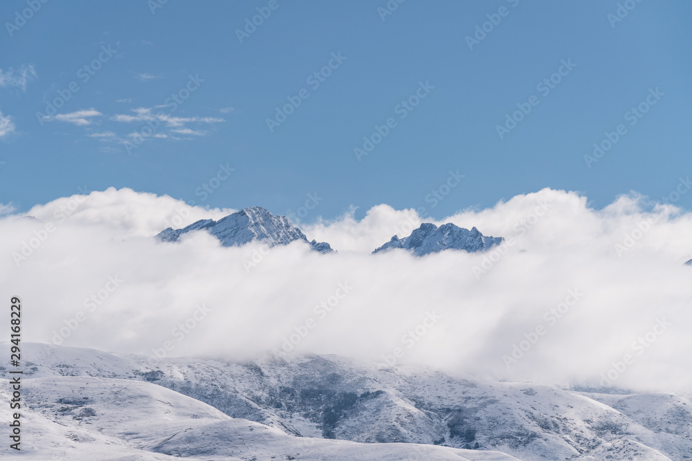 Panoramic snow mountains over white clouds and blue sky