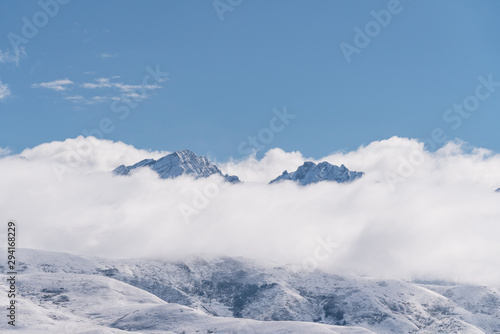 Panoramic snow mountains over white clouds and blue sky © SasinParaksa