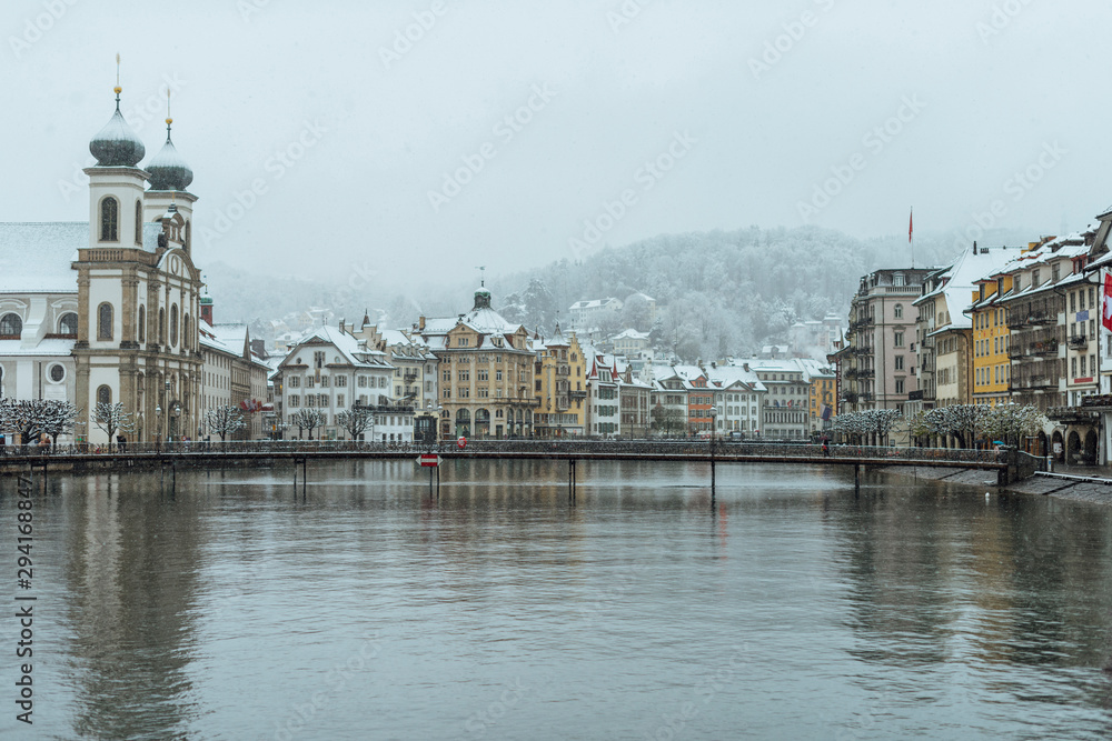 Fototapeta premium The old town of Lucerne with the roofs of the buildings covered with snow, after a snowfall on a cold winter day.