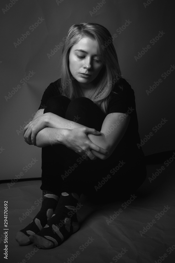 Sad young woman sitting on the floor. Black and white Sad young woman sitting on the floor. Black and white
