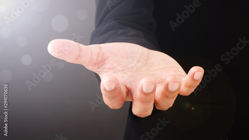 Close up Asian Man standing and shows outstretched hand with open palm on Light of Len flare and Boke blue background. COPY SPACE. photo