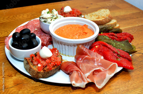Close up of mixed platter with various cheeses, olives, peppers, toast, cured meats, salami and bruschetta 