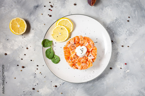 Delicious avocado and salted salmon tartar on concrete background