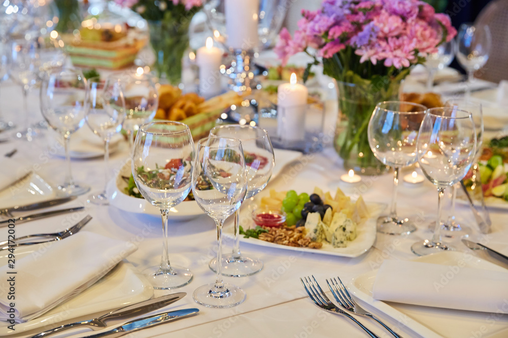 Table setting for guests in a restaurant, on the table forks and glasses for wine - flowers in a vase and a candle on the table