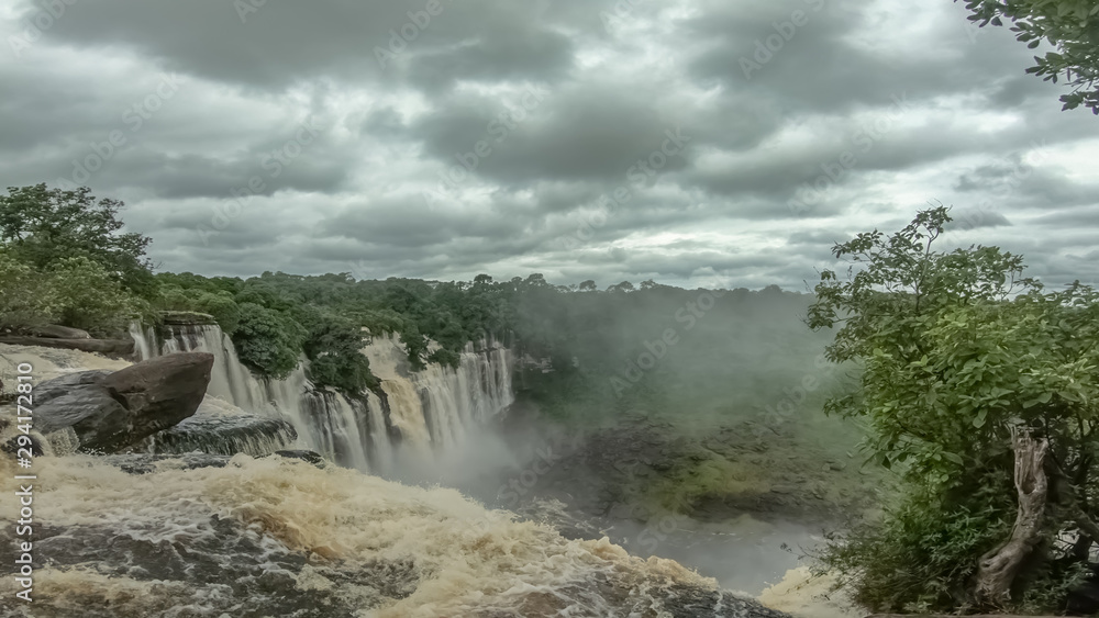 View of the Kalandula waterfalls on Lucala river, tropical forest and cloudy sky as background
