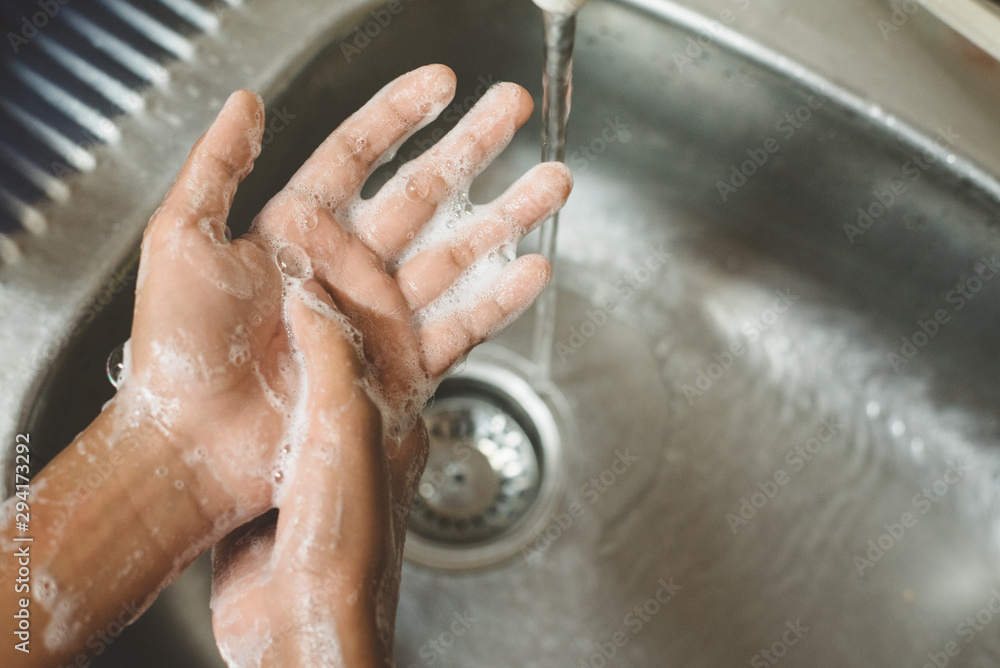 Fototapeta premium closeup of a boy scrubbing soapy hand against washbasin. Concept of a hand hygiene and global handwashing day