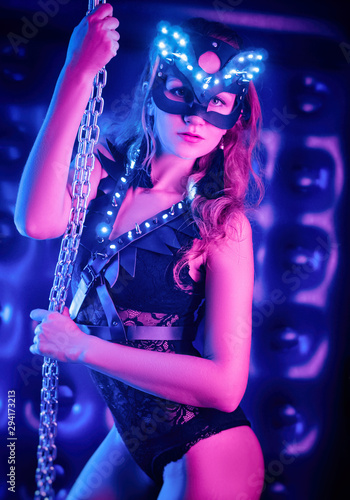 A girl in a sexy cat and party costume posing in a neon set for Halloween